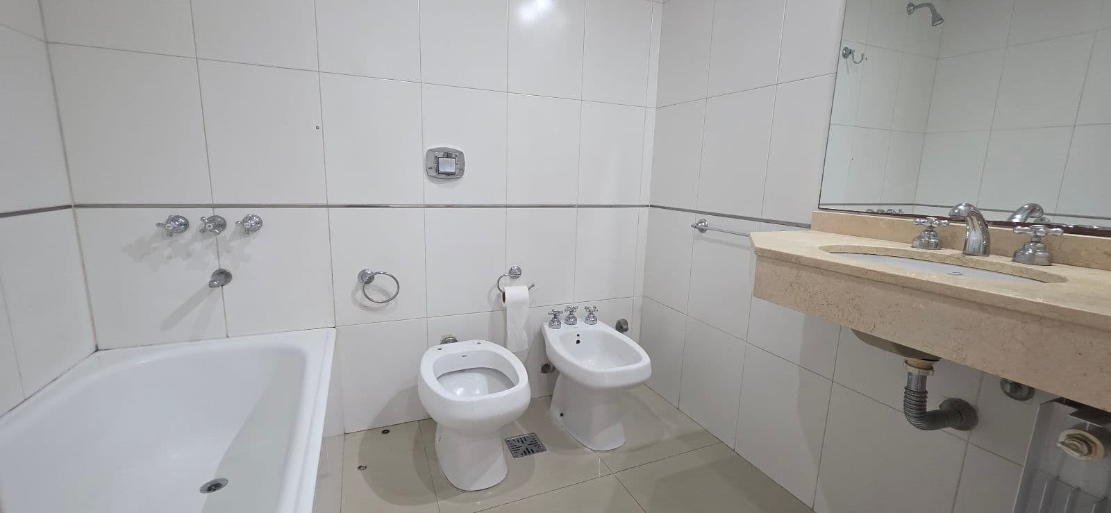 Baño completo con bañera, inodoro, bidet y vanitory con espejo.