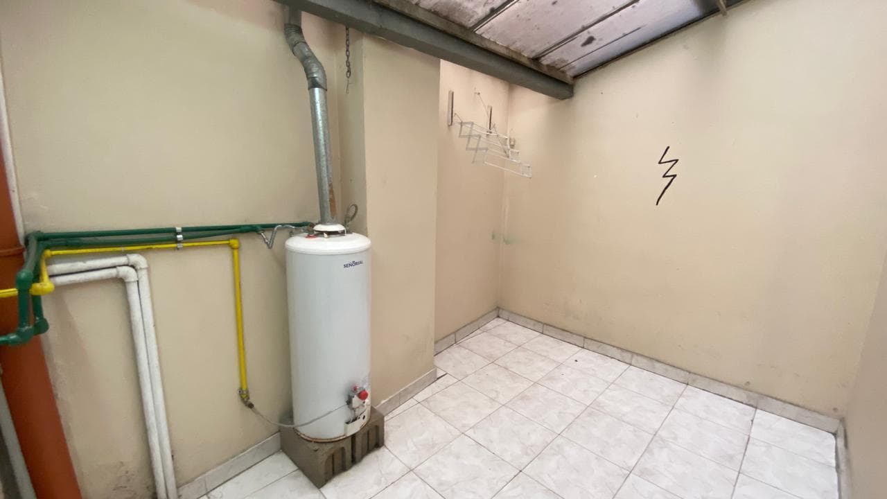 Lavadero con termotanque, cañerías, tendedero de ropa y piso de baldosas.