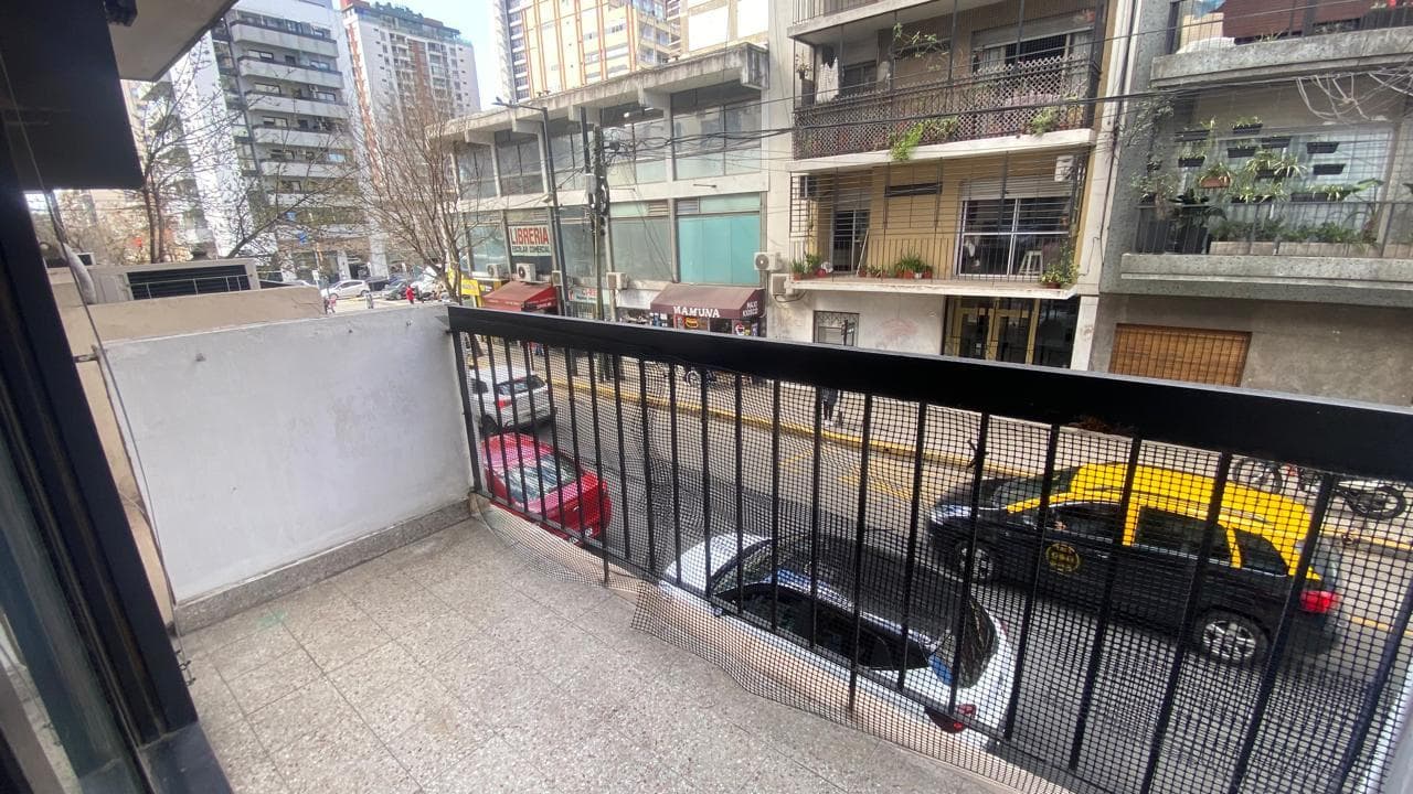 Vista desde el balcón a la calle, edificios, árboles y autos.