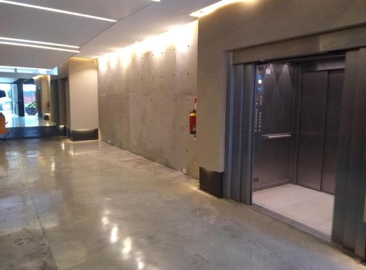 Pasillo de un edificio con ascensor abierto y extintor.