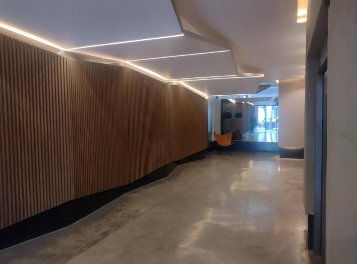 Pasillo moderno con iluminación LED en el techo y pared de listones de madera.