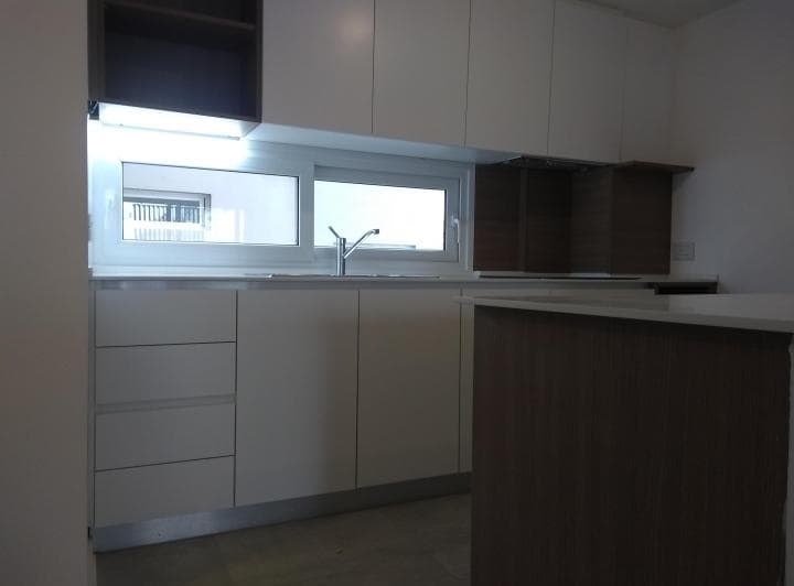 Cocina con mesada, bacha, grifería, alacenas blancas y ventana.