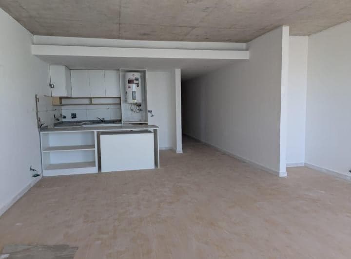 Cocina integrada con muebles blancos y termotanque, espacio abierto.