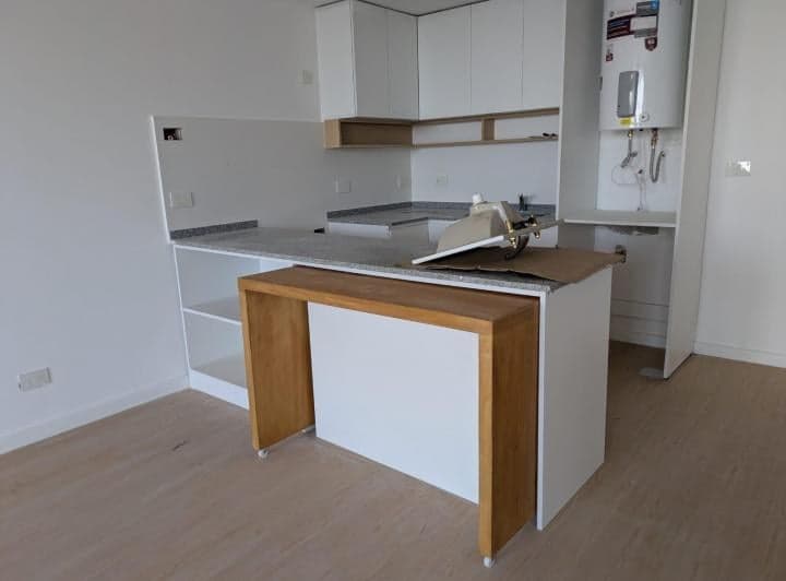 Cocina integrada con mesada de granito, bacha y mesa de madera.