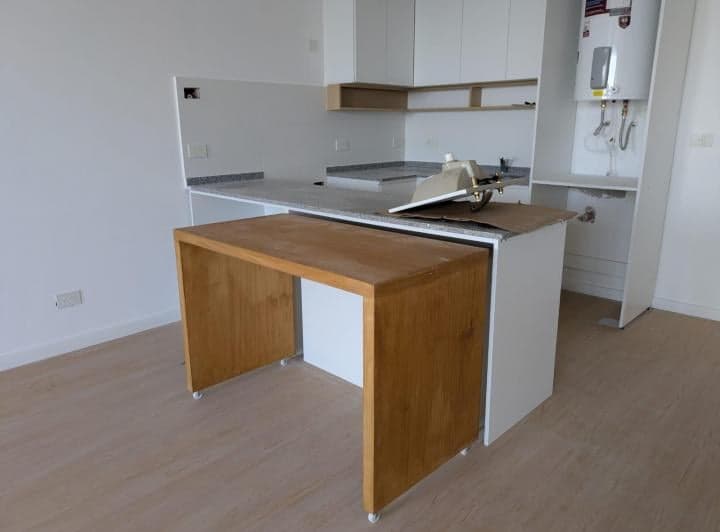 Cocina con mesada de granito, bacha y mesa extensible de madera.