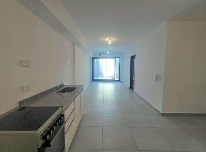 Cocina integrada con anafe, mesada, y vista a ambiente principal con balcón.