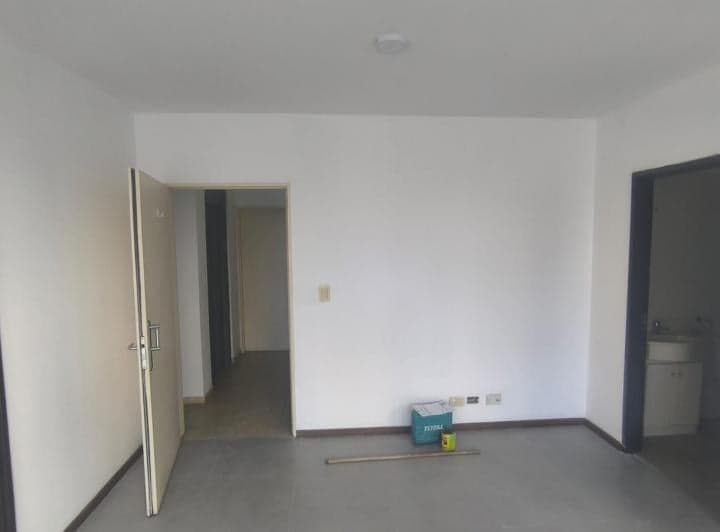 Living vacío con puerta de entrada, acceso a pasillo y entrada a la cocina.