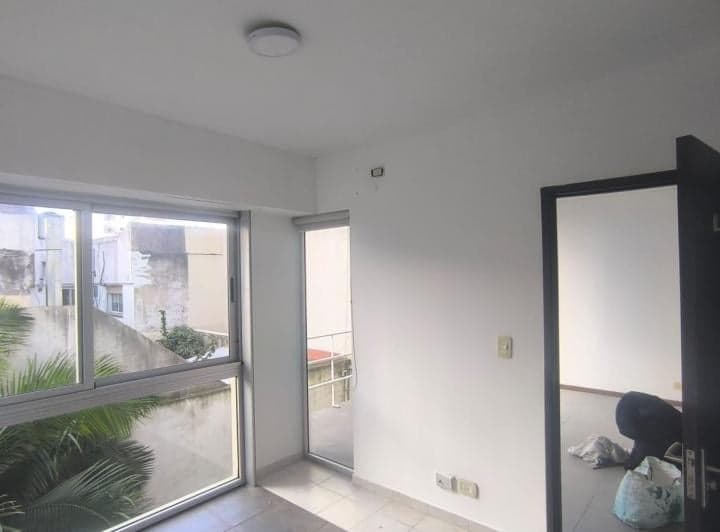 Dormitorio vacío con puerta ventana, ventanas y vista al exterior.