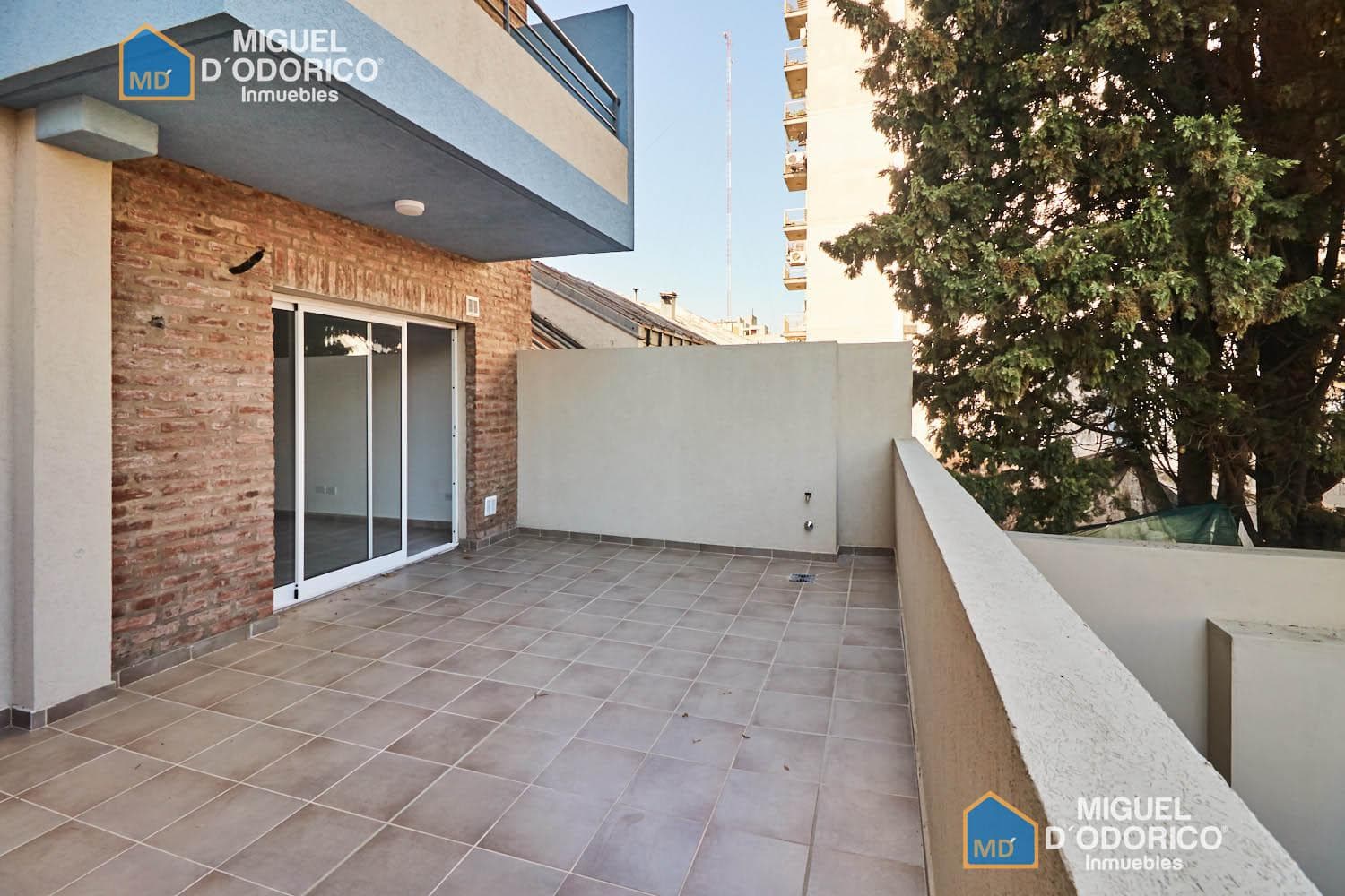 Balcón terraza amplio con baranda y vista a edificios y árboles.