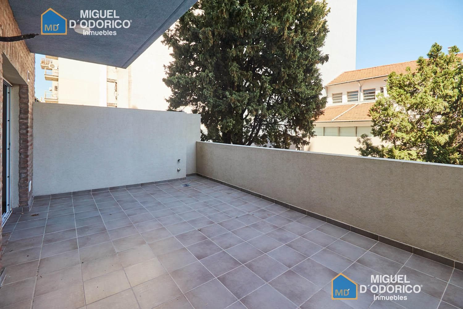 Balcón terraza con paredes claras y vista a la ciudad y árboles.