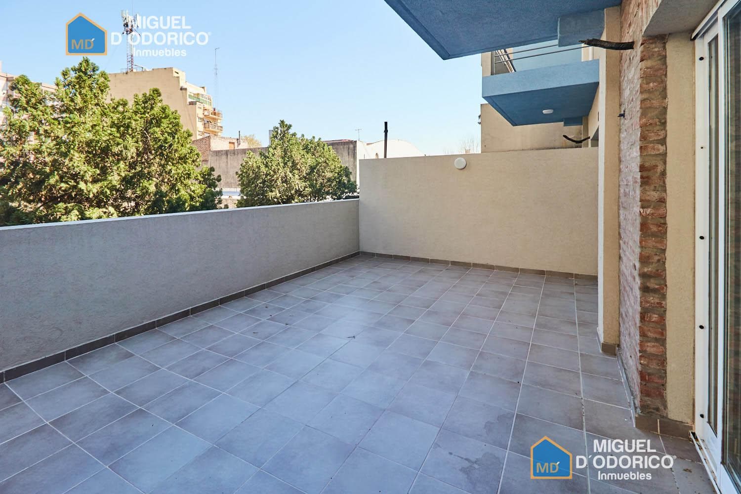Balcón terraza con baranda, vista a edificios y árboles.