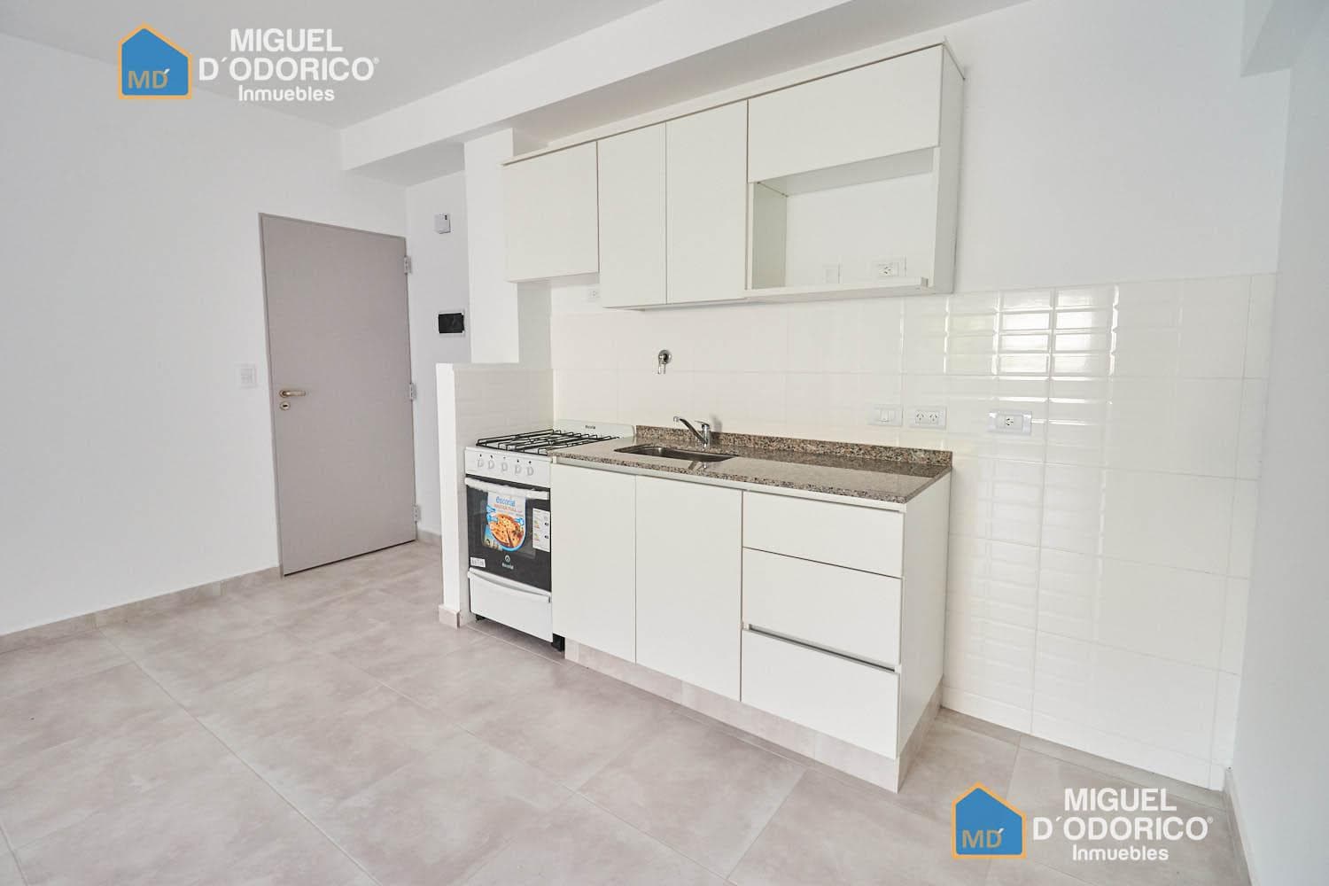 Cocina con muebles blancos, anafe y horno.