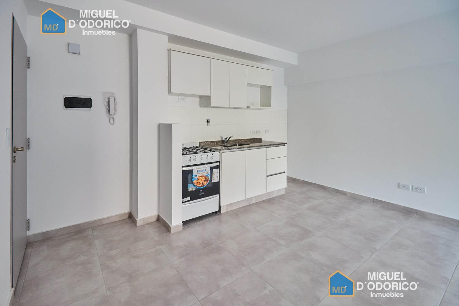 Cocina integrada con muebles blancos y anafe.