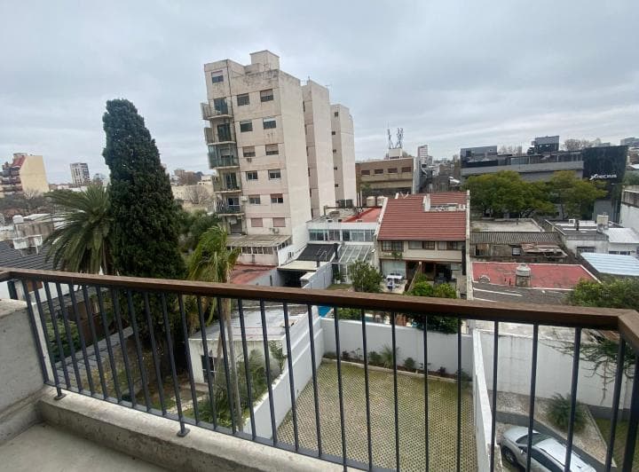 Vista desde el balcón a edificios, patio y un automóvil.