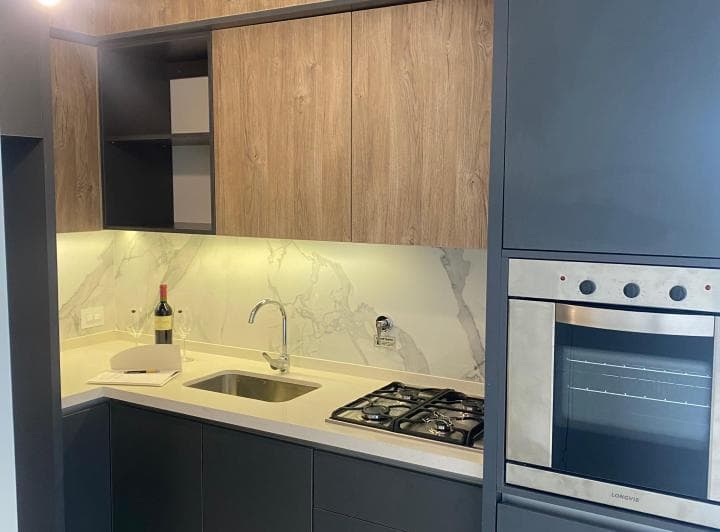 Cocina con mesada, anafe, horno y alacenas de madera.