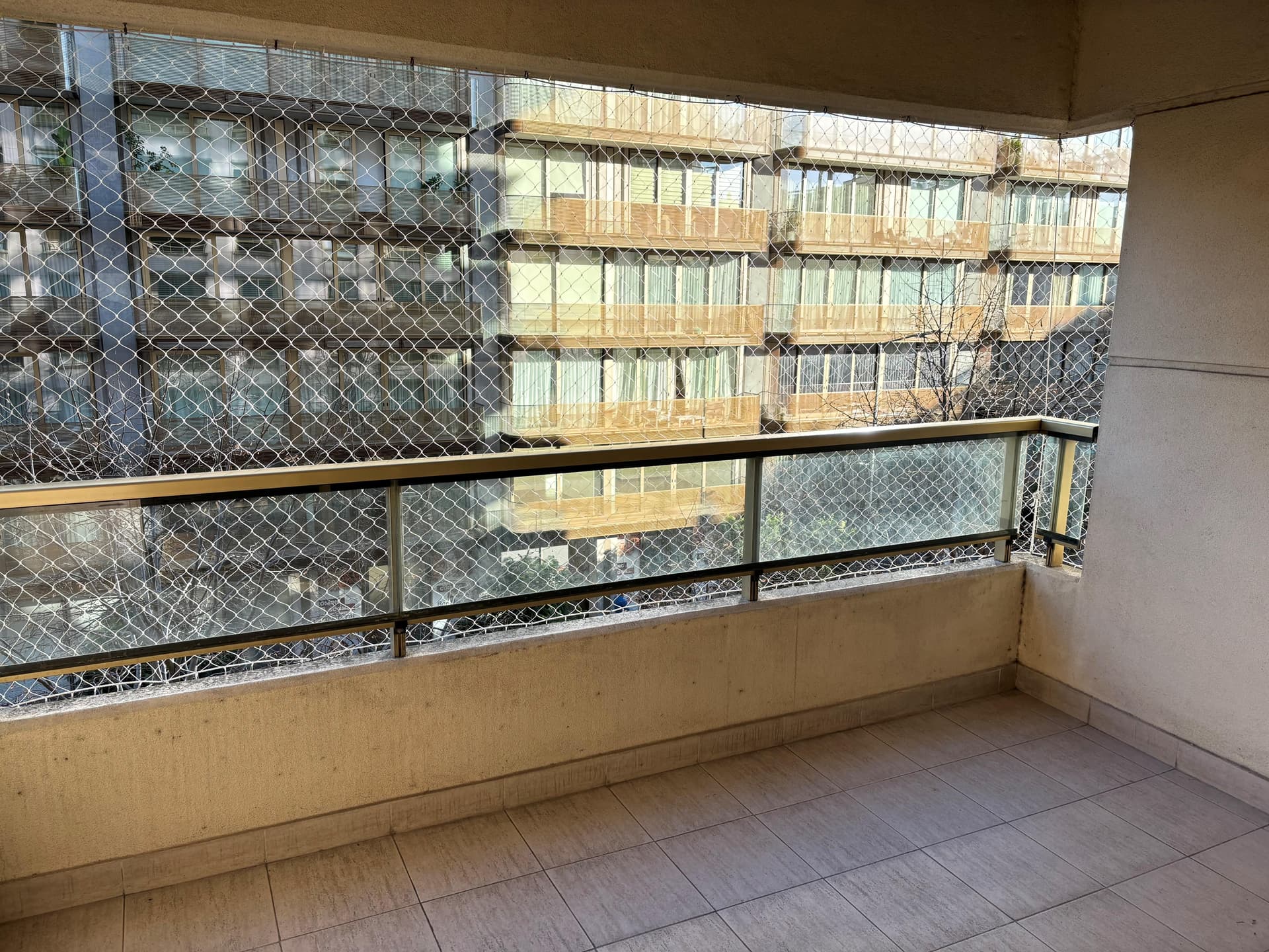 Balcón con red de seguridad y vista a edificios.