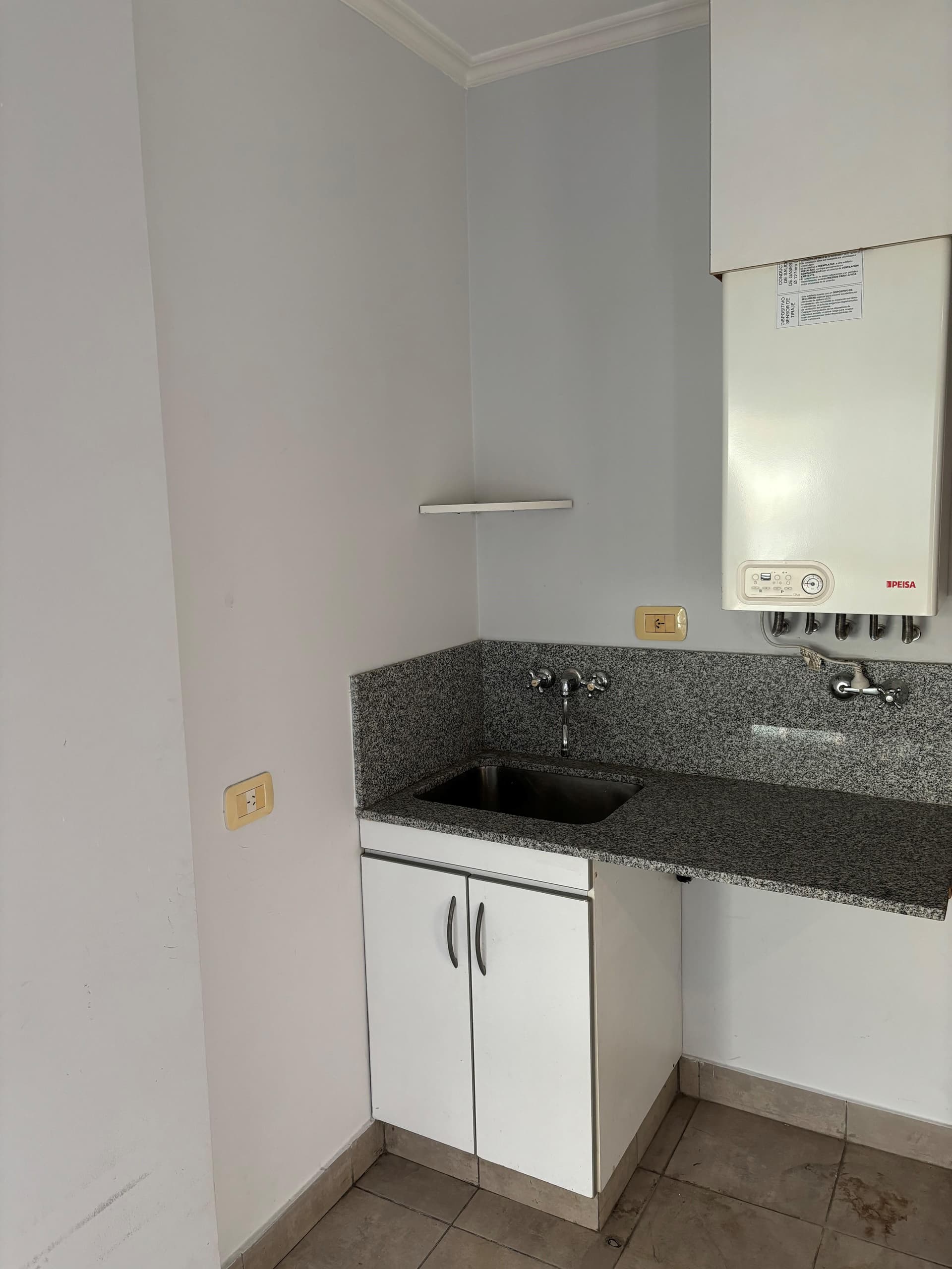 Lavadero con bacha, termotanque y mesada de granito.
