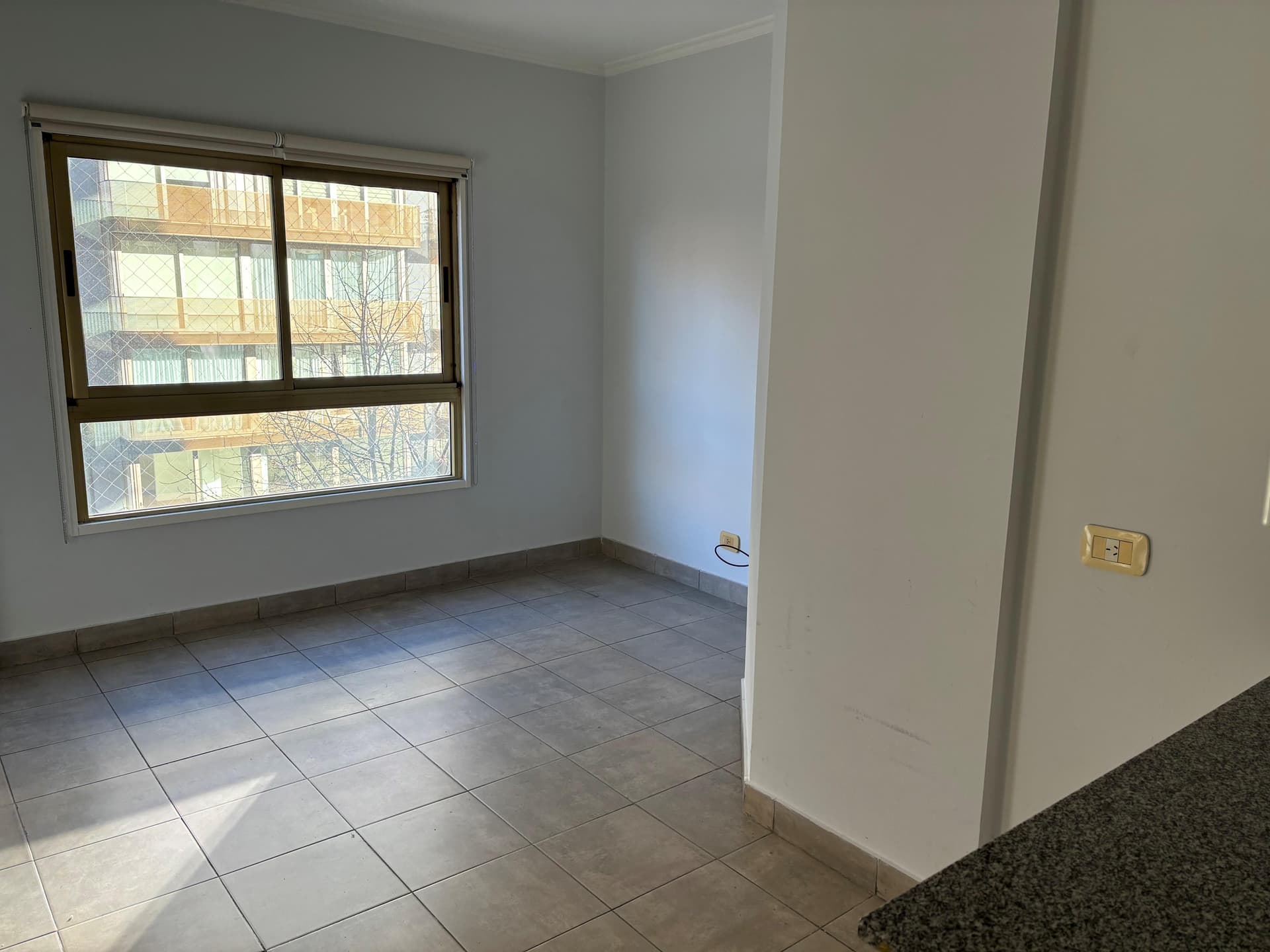Dormitorio vacío con ventana y piso de cerámica.