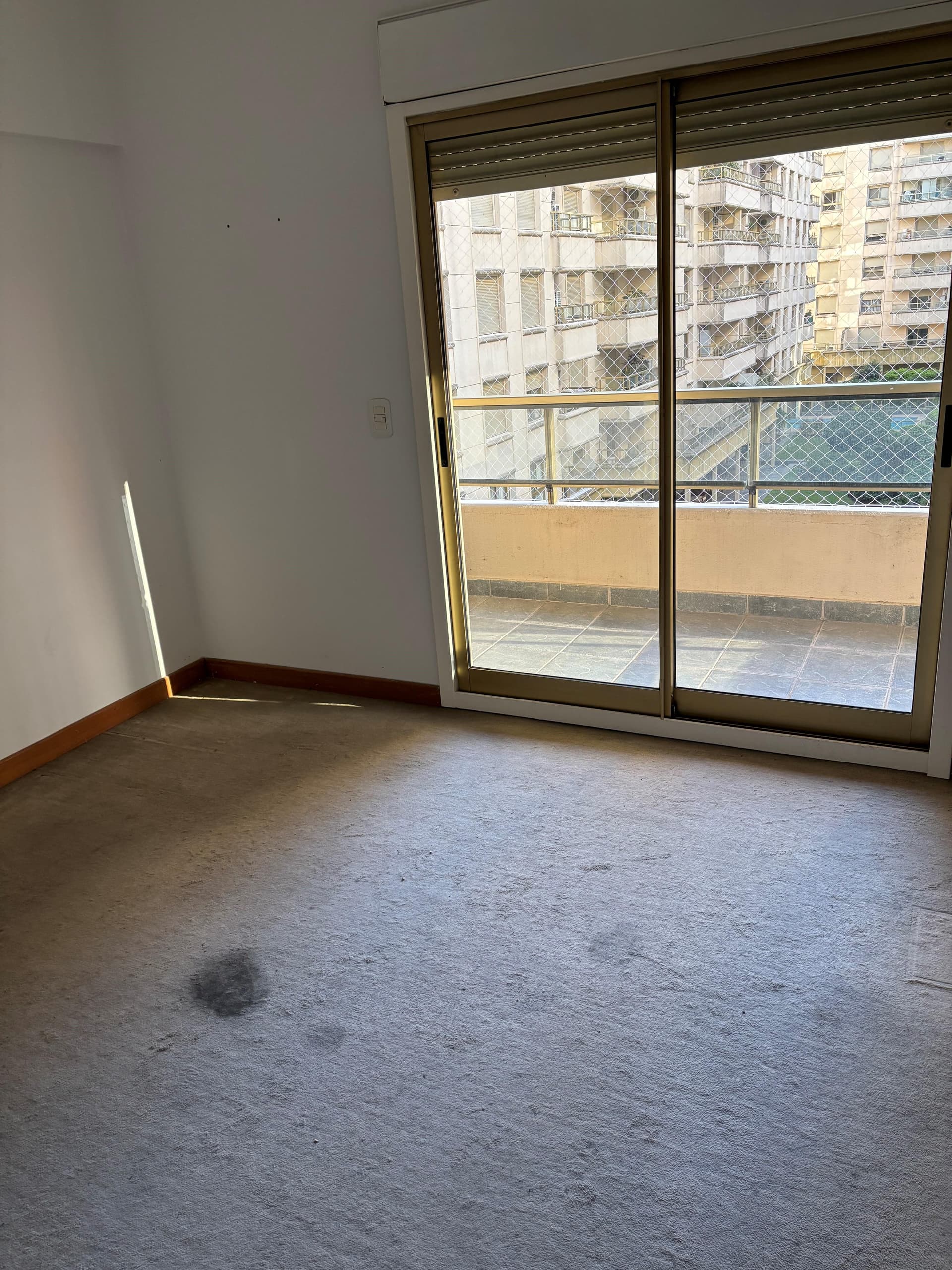Dormitorio con alfombra y salida al balcón.