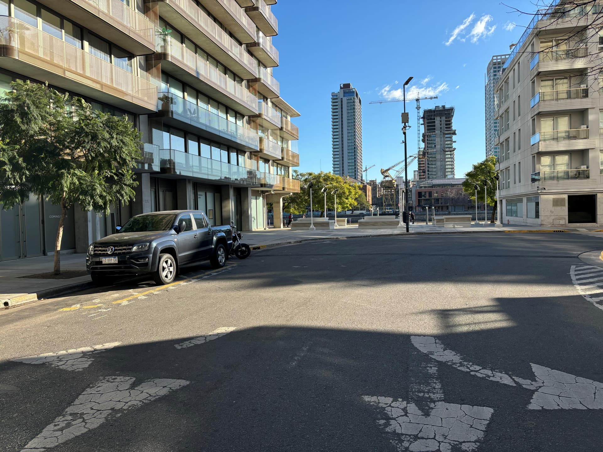 Vista de calle con edificios modernos y grúas.