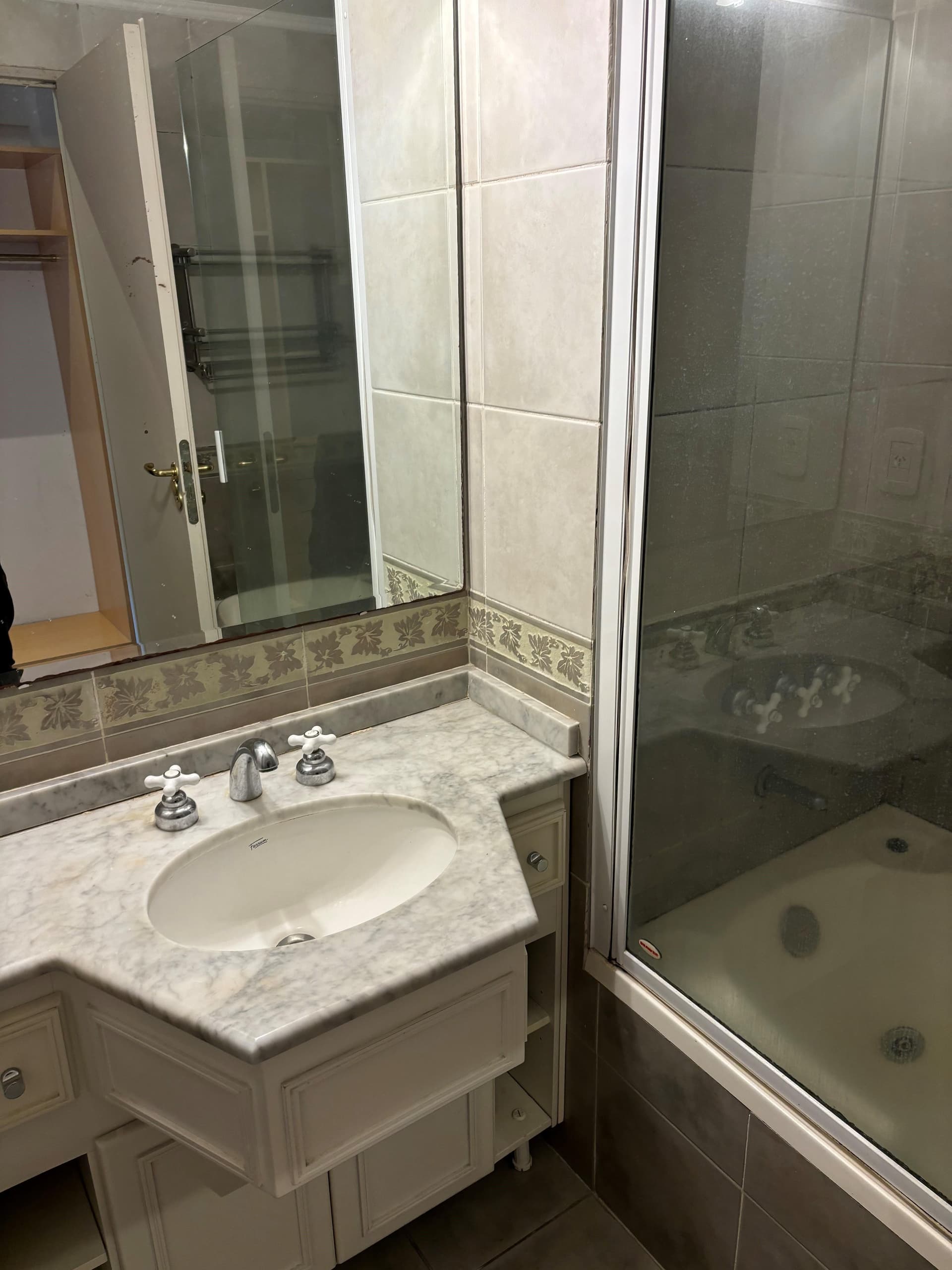 Baño completo con vanitory de mármol y ducha con mampara.