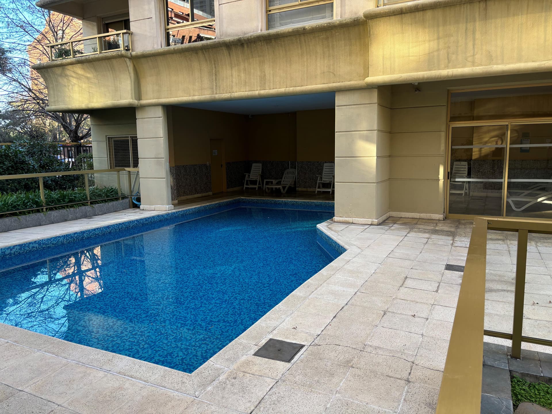 Pileta de natación con área techada para reposeras.