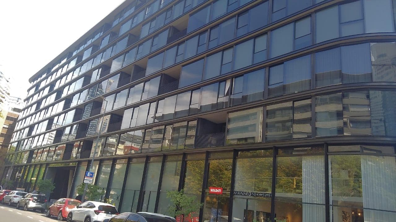 Parte baja del edificio moderno de vidrio con locales comerciales.