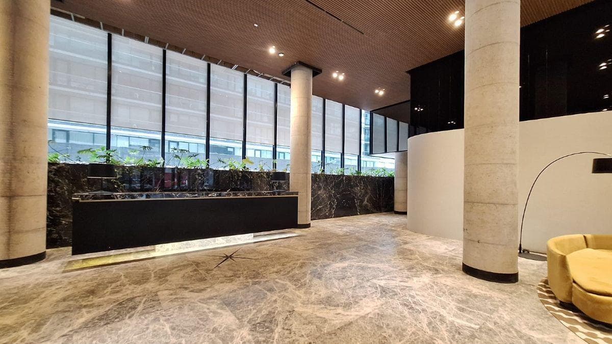 Lobby del edificio con piso de mármol, columnas y mobiliario moderno.