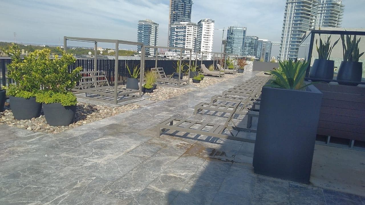Terraza con reposeras, plantas y vistas panorámicas de la ciudad.