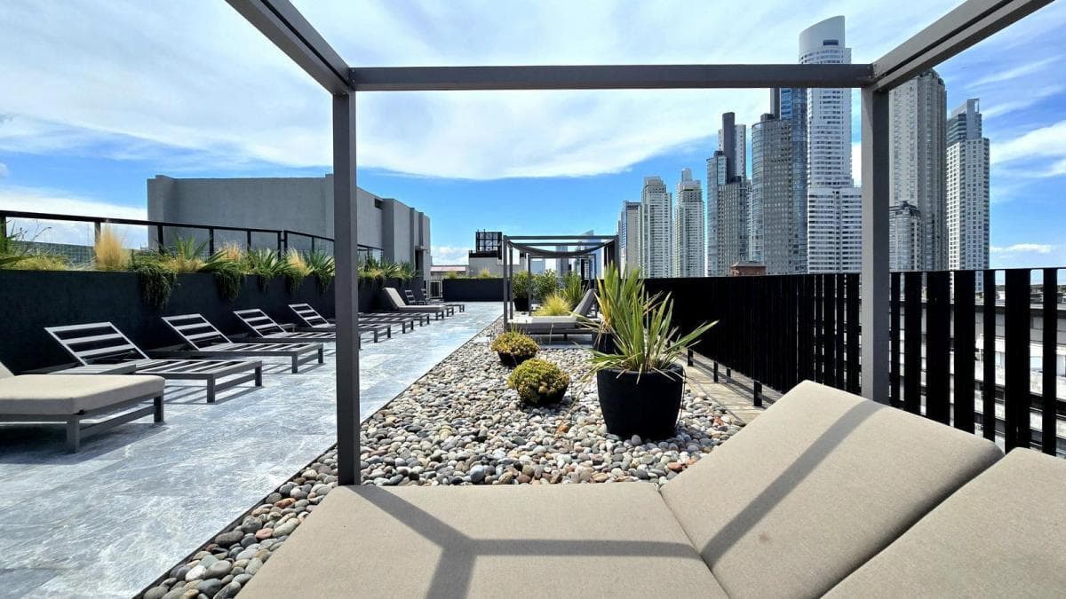 Terraza del edificio con reposeras, jardines y vistas a la ciudad.