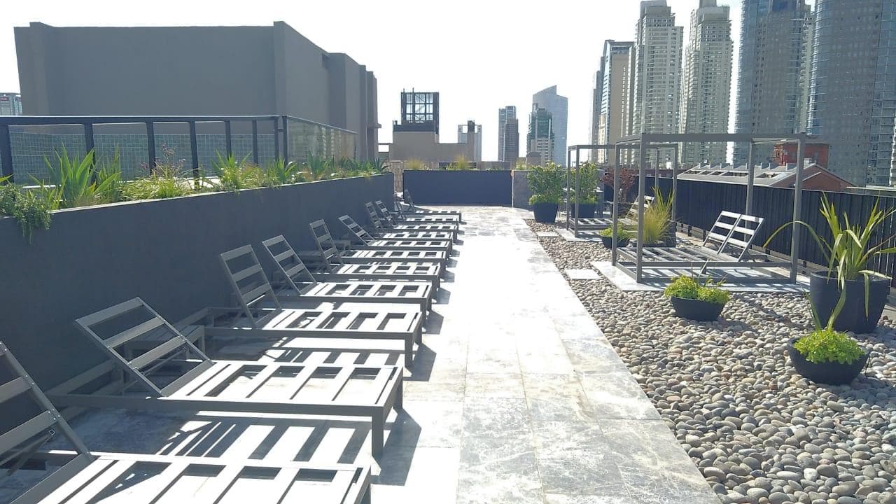 Terraza del edificio con varias reposeras y decoración de piedras.