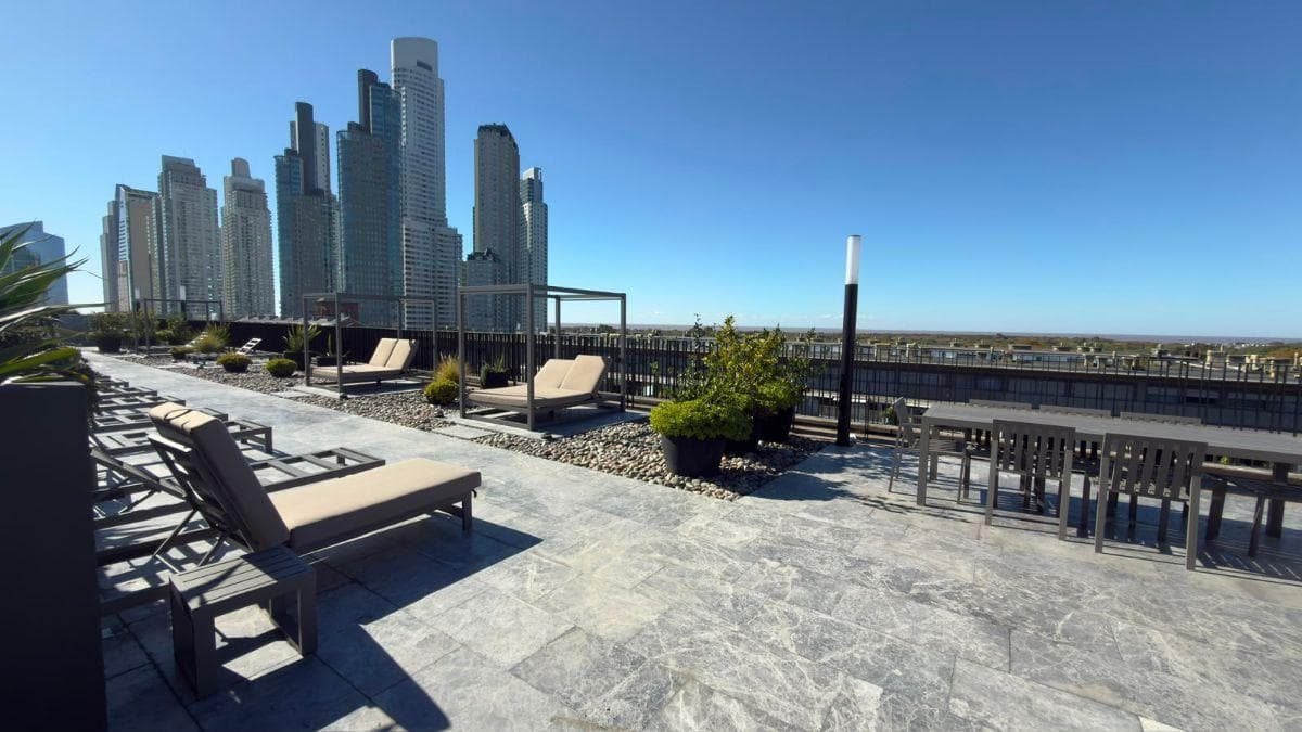 Terraza con reposeras, mesas y vistas al horizonte de la ciudad.