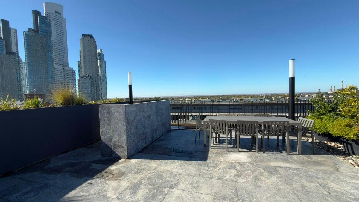 Terraza con mesa de comedor exterior, sillas y vista a la ciudad.