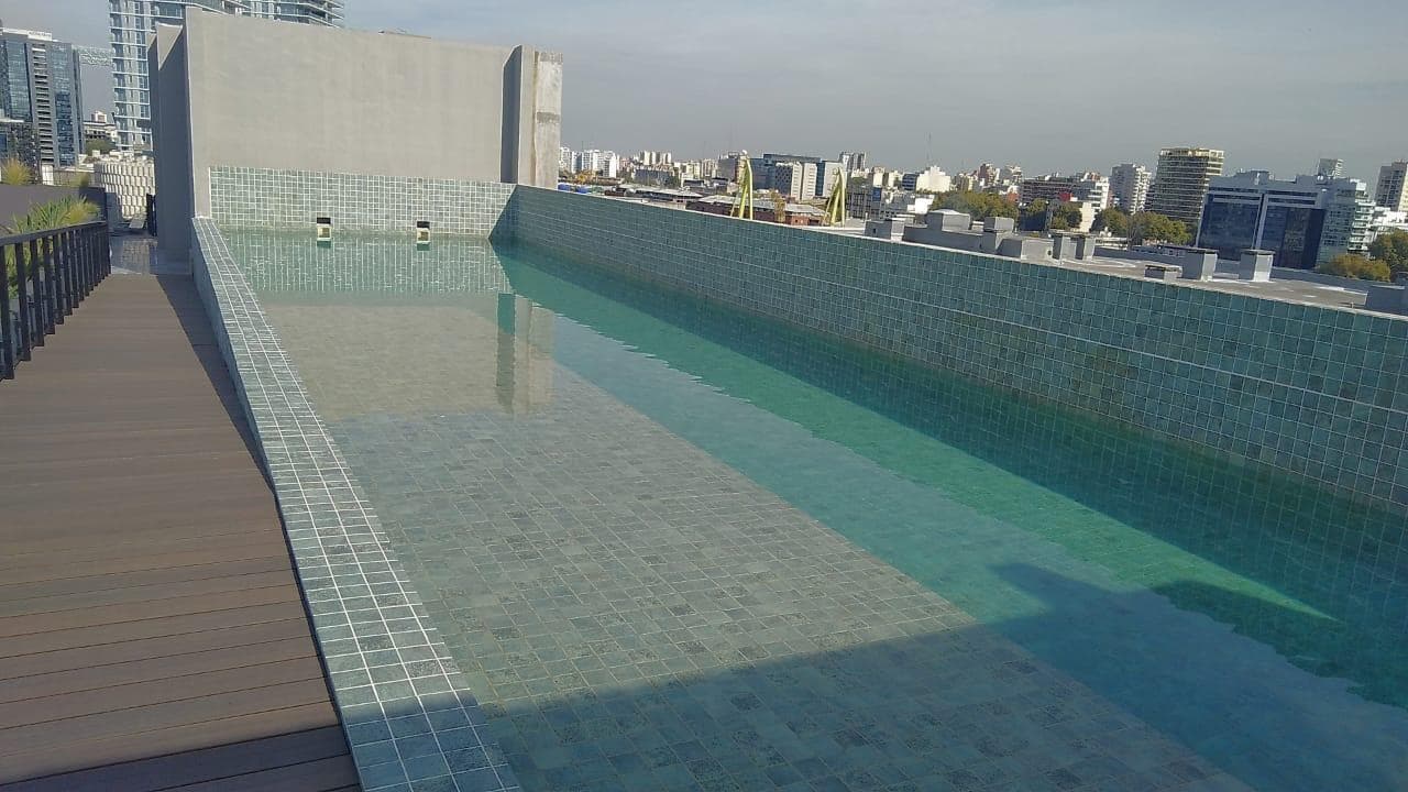 Pileta rectangular en la terraza con deck de madera alrededor.