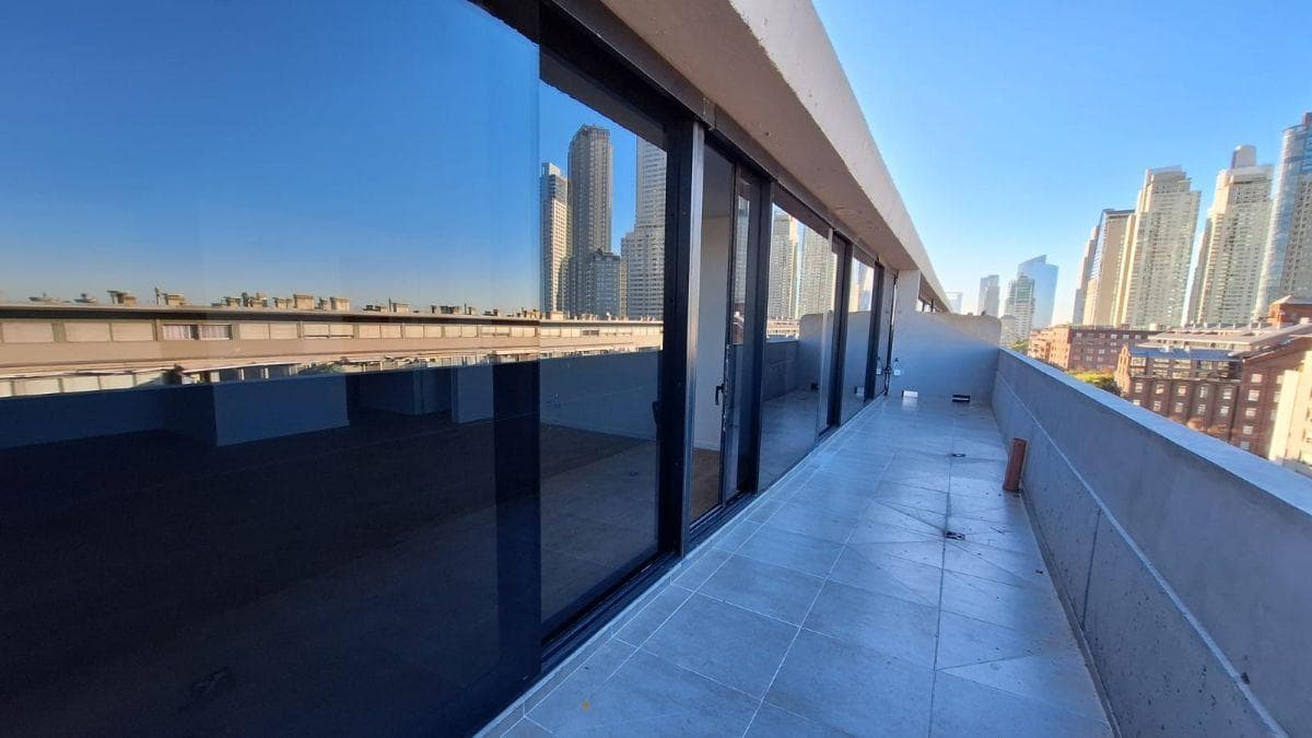 Balcón exterior largo con vista a los edificios y la ciudad.