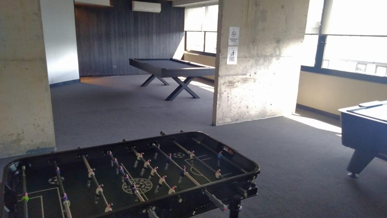 Salón de juegos con metegol y una mesa de pool.