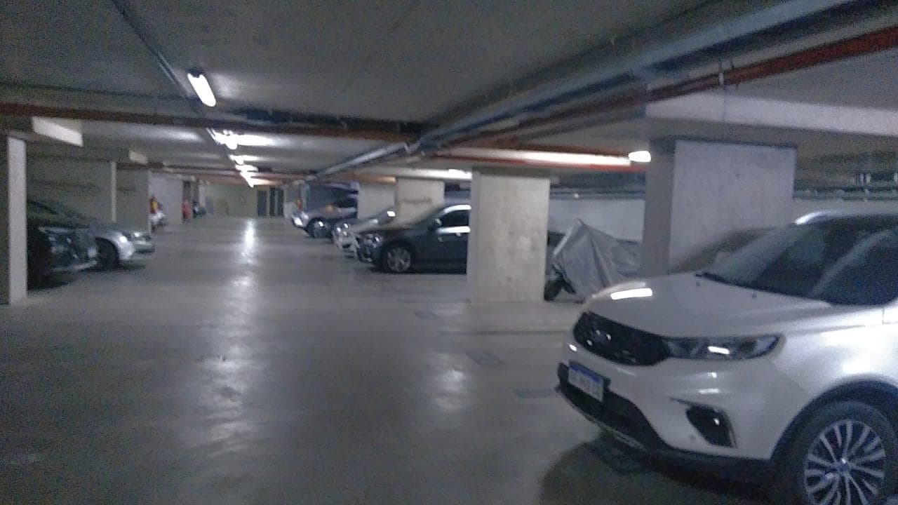 Garaje subterráneo iluminado con varios autos estacionados en fila.