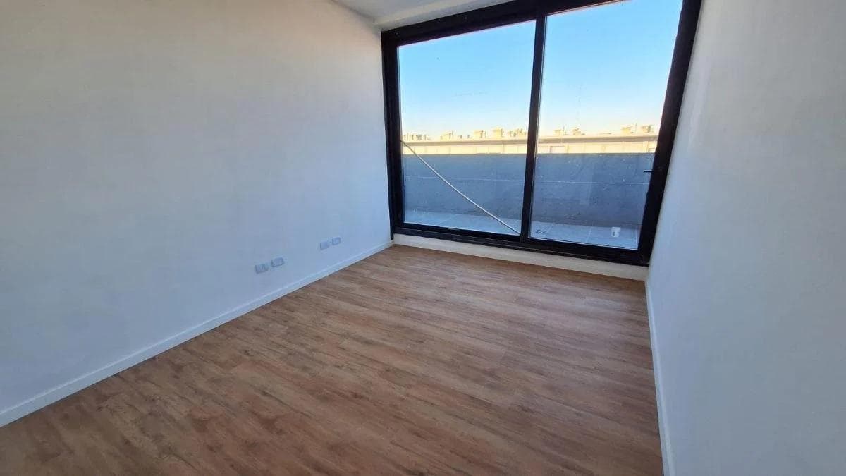 Dormitorio vacío con amplio ventanal ofreciendo vistas exteriores.