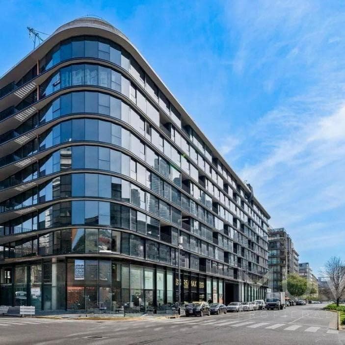 Fachada de edificio moderno con ventanales de vidrio en la esquina.