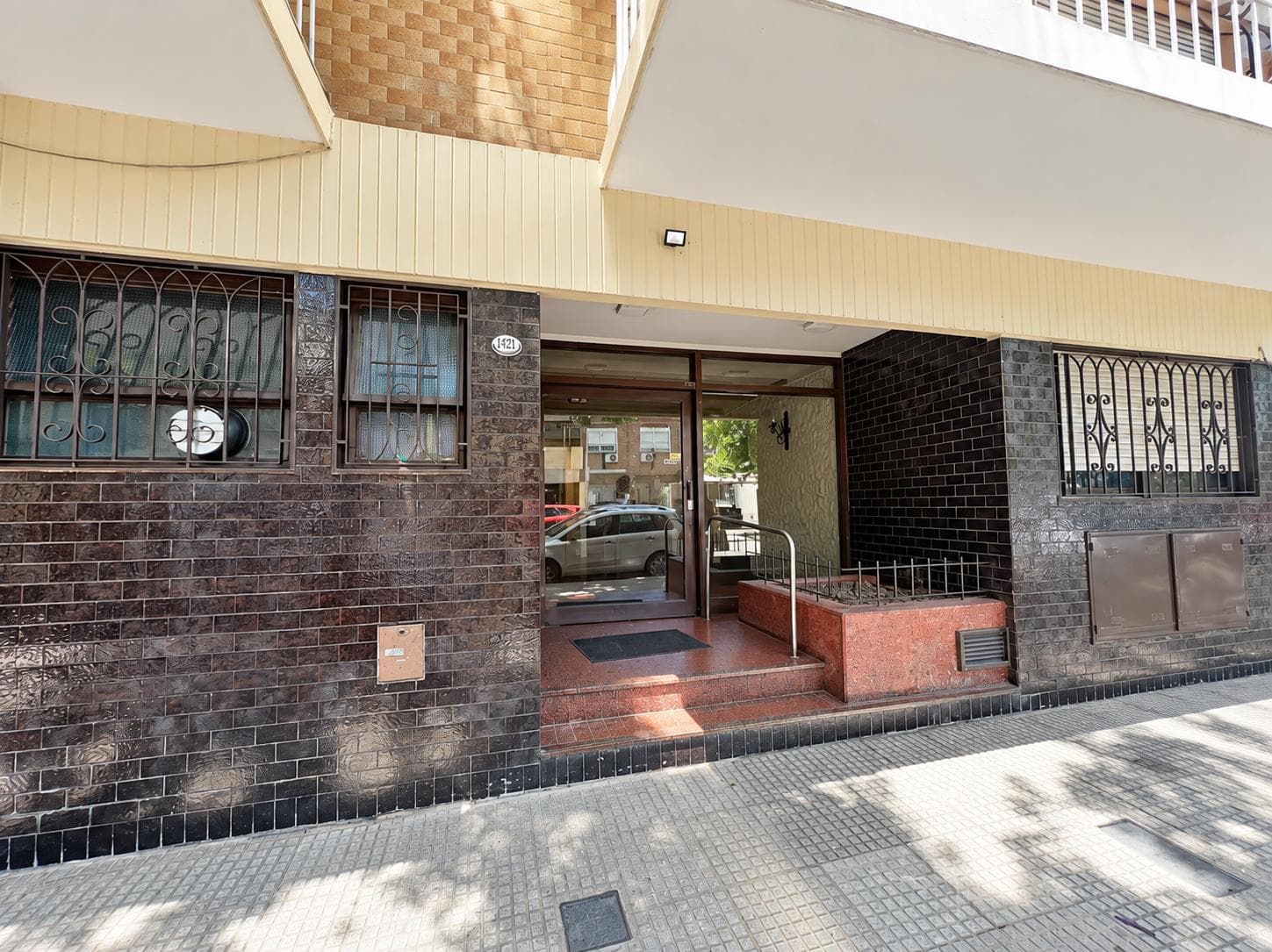 Fachada de edificio de departamentos con puerta de entrada y rejas en ventanas.