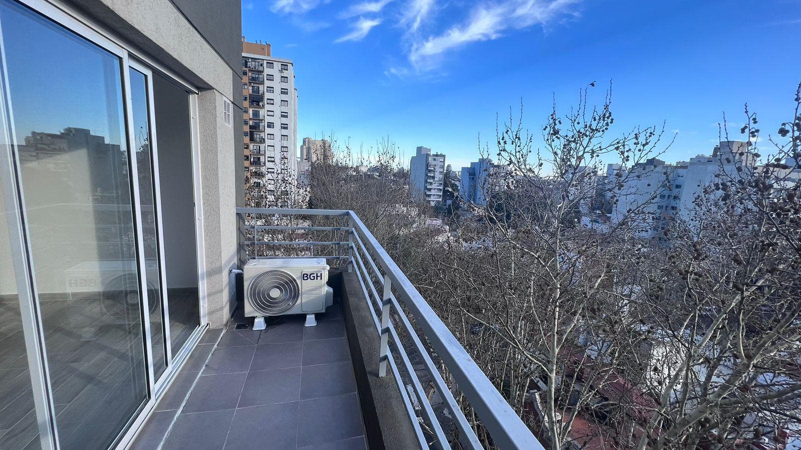 Balcón estrecho con baranda metálica y vistas a la ciudad.