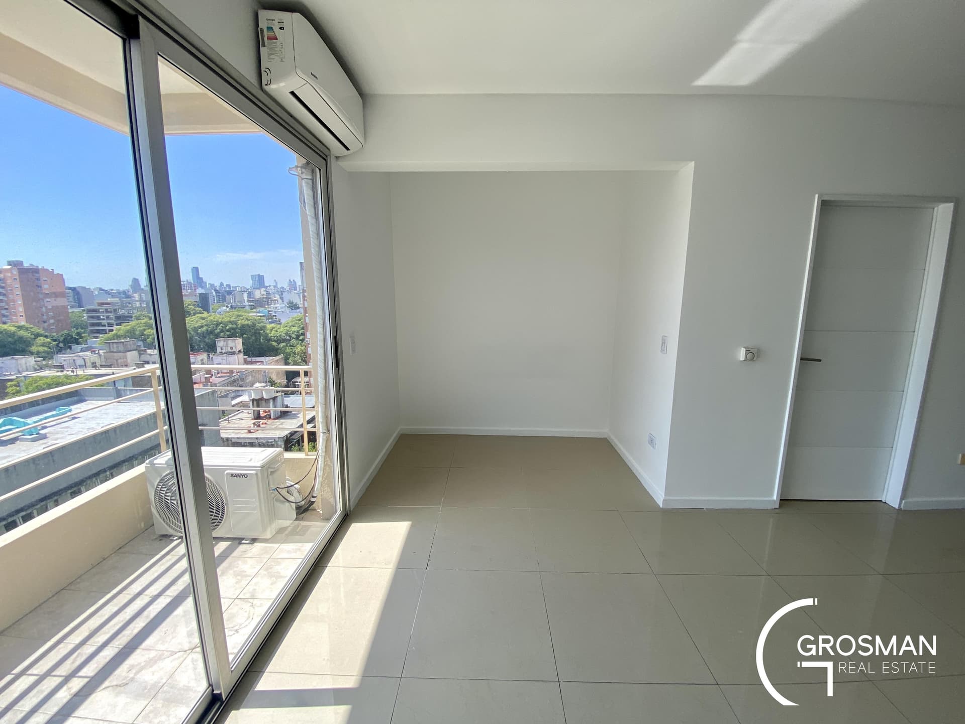 Living vacío con salida al balcón y aire acondicionado.