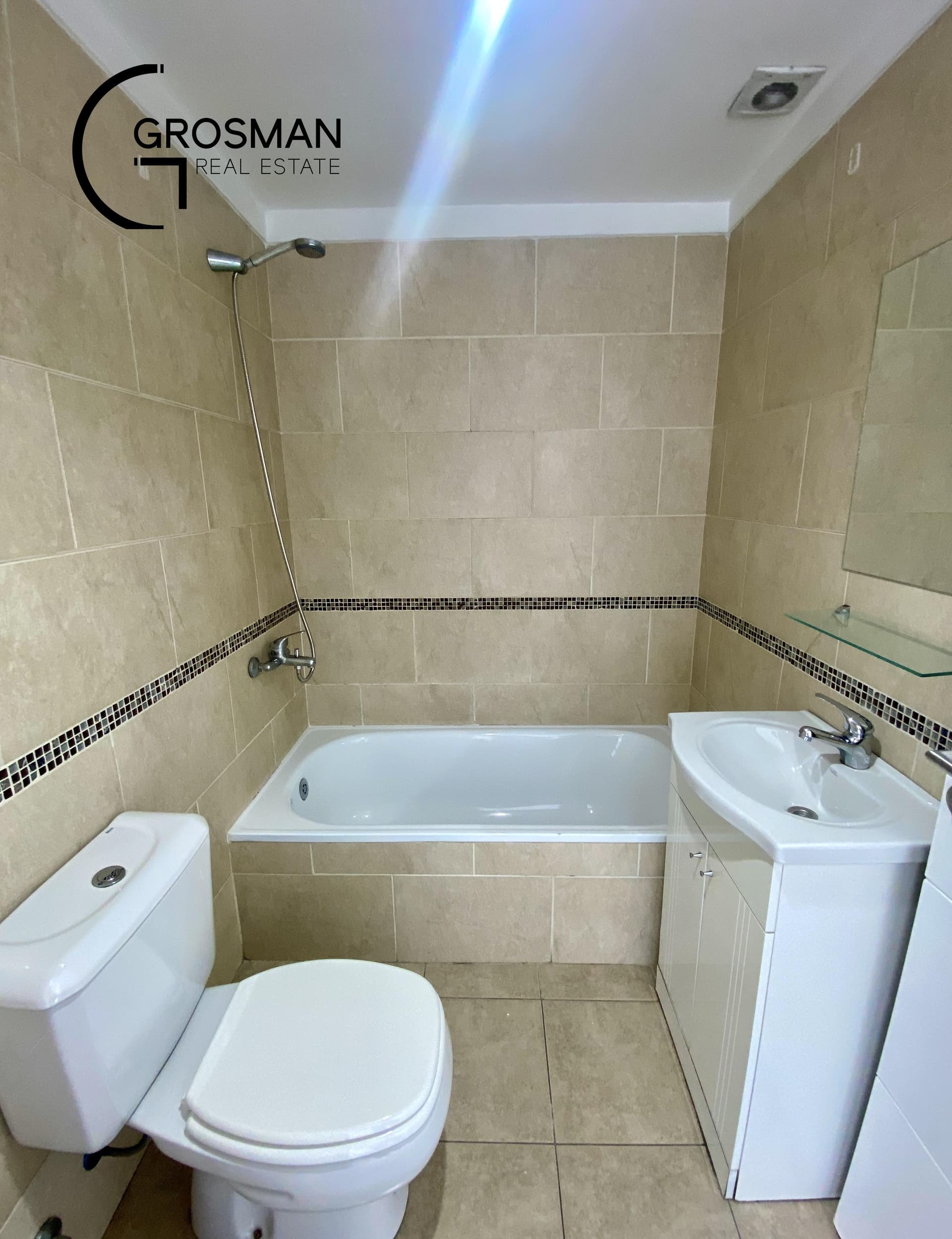Baño con bañera, inodoro, vanitory y ducha en la pared.