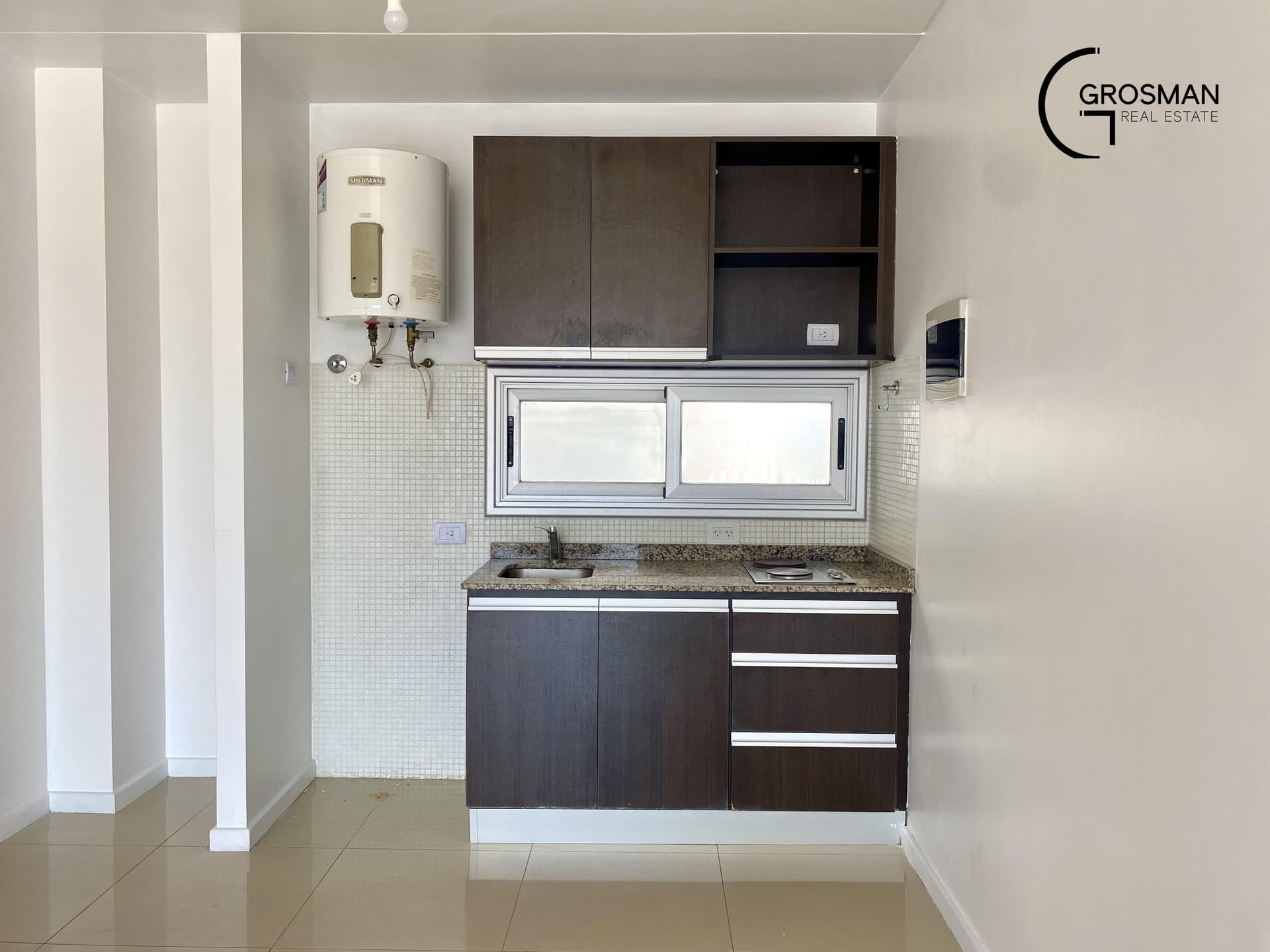 Cocina integrada con mesada, anafe, alacenas y termotanque.