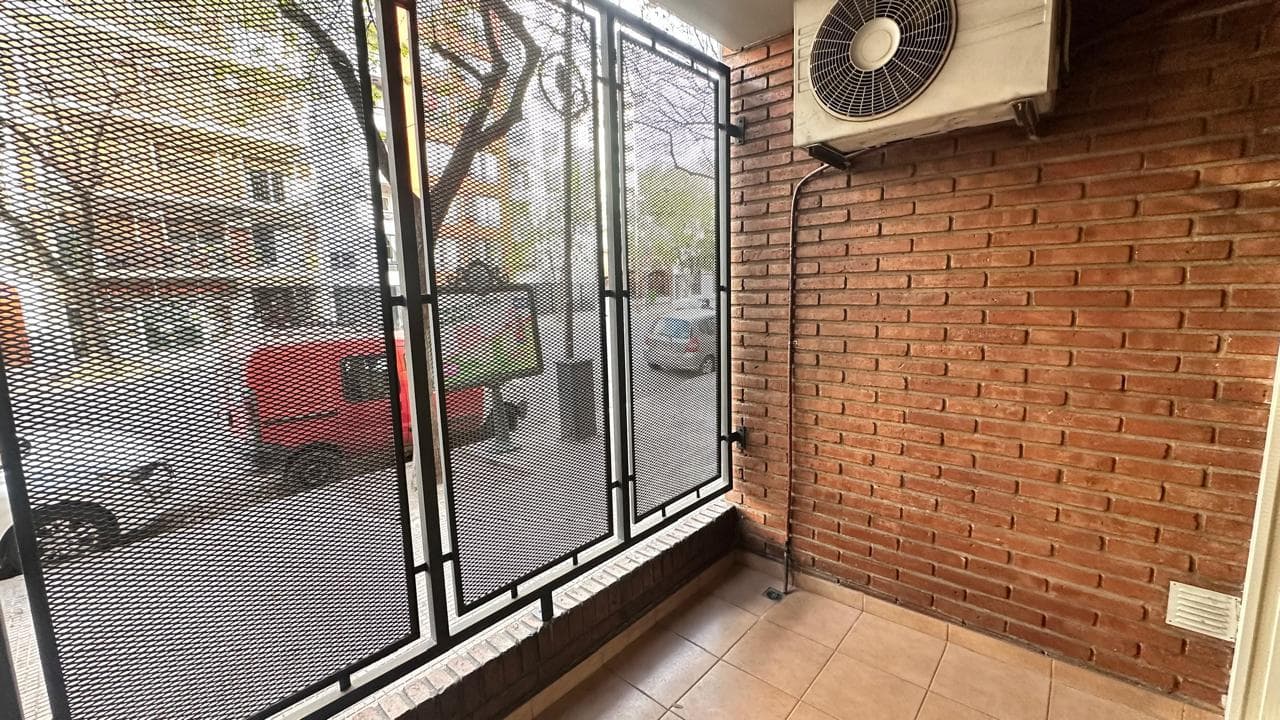 Balcón exterior con pared de ladrillo y rejas de seguridad.