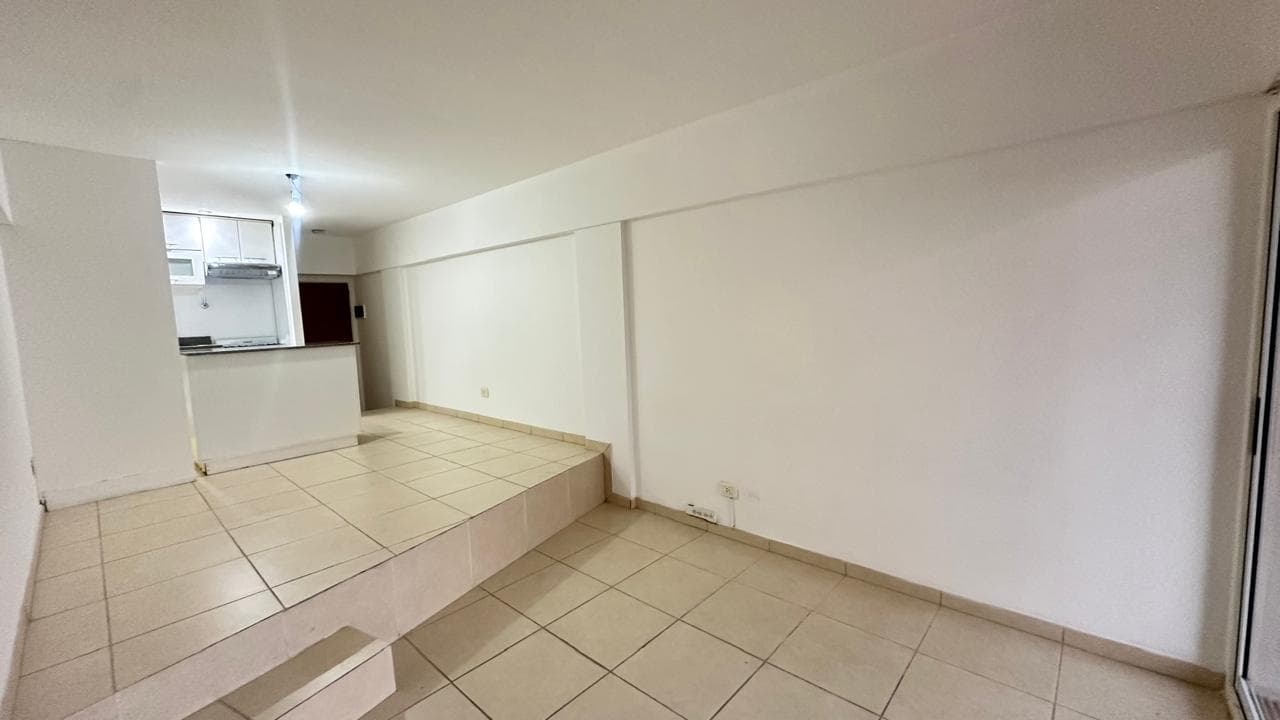 Living amplio y vacío con desnivel y piso de baldosas.