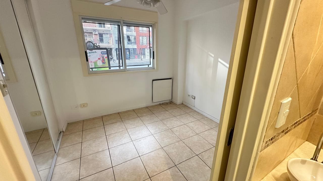 Dormitorio vacío con ventana, placard con espejo y ventilador de techo.