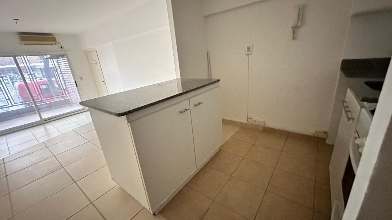 Cocina integrada con barra, vista al living y balcón.