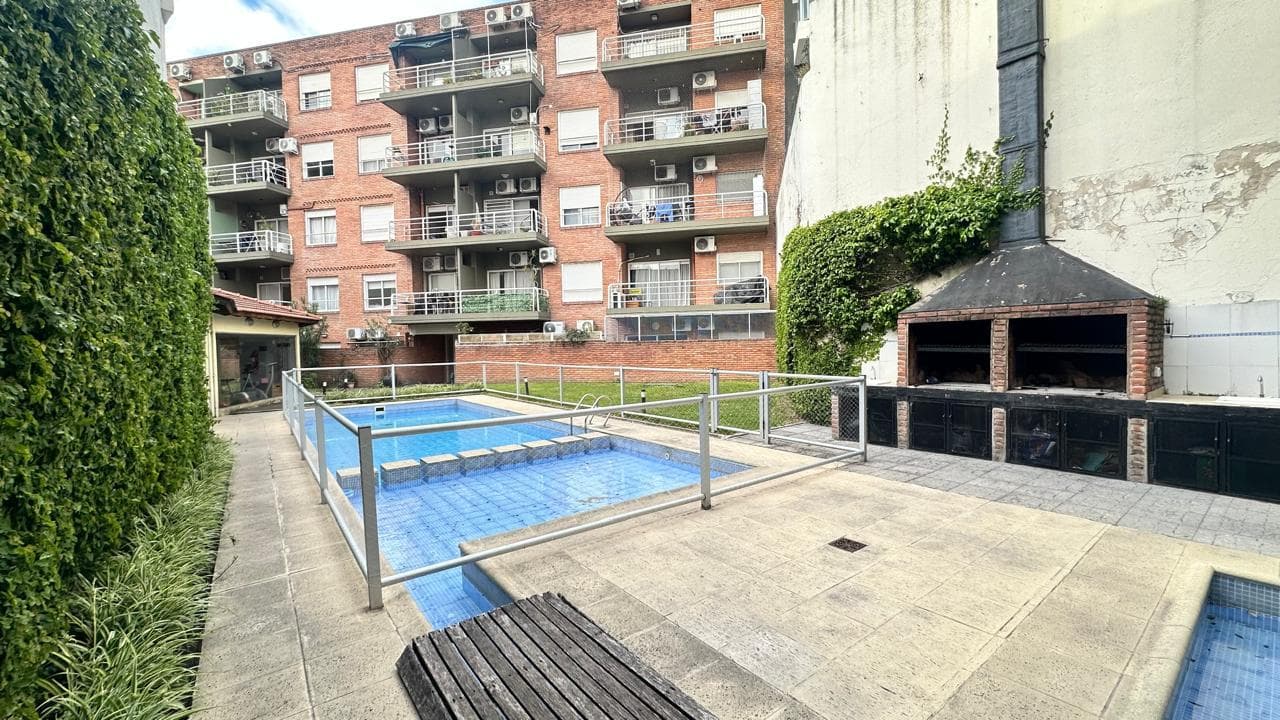 Pileta exterior del edificio con quincho, parrilla y área de solárium.
