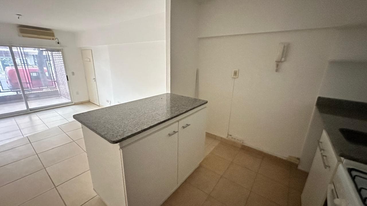 Cocina integrada al living con barra desayunadora y vista al balcón.